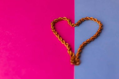 Doku güzel altın şenlikli zinciri pembe mor mavi arka plan ve bir kopya alanı üzerinde bir kalp şeklinde dokuma benzersiz