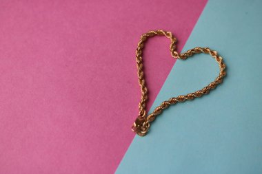 Doku güzel altın şenlikli zinciri pembe mor mavi arka plan ve bir kopya alanı üzerinde bir kalp şeklinde dokuma benzersiz