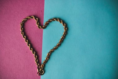 Doku güzel altın şenlikli zinciri pembe mor mavi arka plan ve bir kopya alanı üzerinde bir kalp şeklinde dokuma benzersiz. Konsept: aşk, evlenme teklifi, evlilik, Sevgililer günü