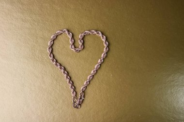 Doku zincirinin bir güzel altın şenlikli bir sarı altın arka plan ve kopya alanı üzerinde bir kalp şeklinde dokuma benzersiz. 