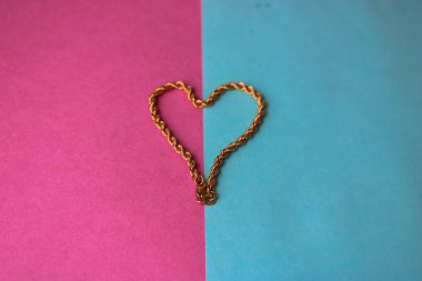 Doku güzel altın şenlikli zinciri pembe mor mavi arka plan ve bir kopya alanı üzerinde bir kalp şeklinde dokuma benzersiz
