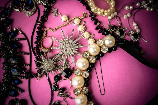 Mooie kostbare glimmende sieraden trendy glamoureuze sieraden set, ketting, oorbellen, ringen, kettingen, broches met parels en diamanten op een roze-paarse achtergrond. Plat lag, top uitzicht, kopie plaats — Stockfoto