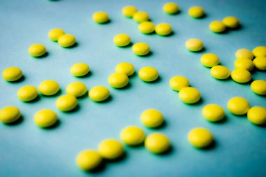 Küçük sarı turuncu güzel tıbbi pharmaceptic yuvarlak hapları, vitamin, uyuşturucu, mavi bir arka plan doku antibiyotik. Konsept: tıp, sağlık. Düz yatıyordu, en iyi görünümü