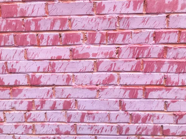 Texture di un bellissimo unico insolito rosa tenero vecchio muro di mattoni incrinati di mattoni rettangolari con cuciture dipinte con rosa vecchia vernice squallida. Lo sfondo — Foto Stock