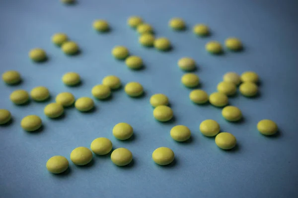 Маленькие желто-оранжевые красивые лечебные круглые таблетки, витамины, лекарства, антибиотики на синем фоне, текстура. Концепция: медицина, здравоохранение. Плоский, вид сверху — стоковое фото