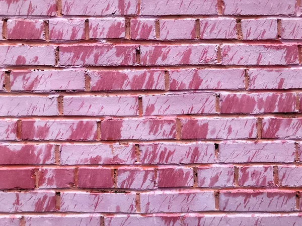 Textur einer schönen einzigartigen ungewöhnlichen rosa zarten alten rissigen Ziegelwand aus rechteckigen Ziegeln mit Nähten mit rosa alter schäbiger Farbe bemalt. der Hintergrund — Stockfoto