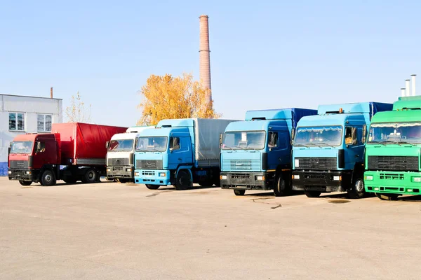 Grands camions lourds avec cabines et remorques se tiennent dans une rangée prêt pour la livraison de marchandises à la raffinerie industrielle dans le contexte des tuyaux, atelier de logistique de transport — Photo