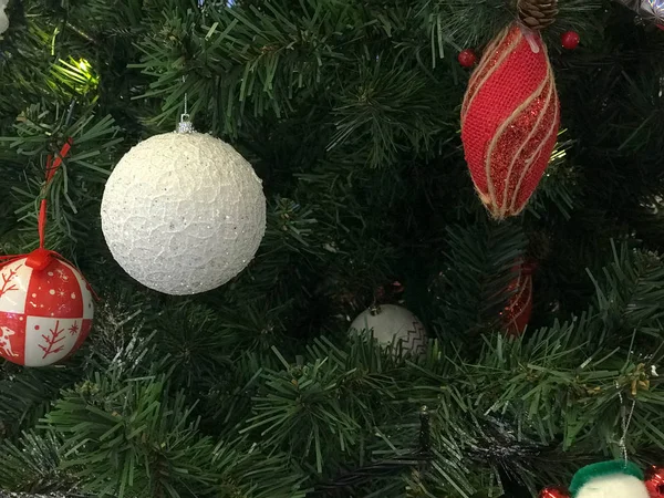 Festive multicolored beautiful shiny fancy balls, toys, gift boxes, decorations on the Christmas green tree with needles and branches for the New Year. Background, texture