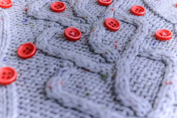 Mooi patroon van een zachte warme natuurlijke trui met een gebreide patroon van garen en rode kleine ronde knoppen voor het naaien. De achtergrond — Stockfoto