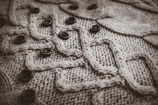Prachtige textuur van een zachte warme natuurlijke trui met een gebreide patroon van garen en zwart / wit kleine ronde knoppen. De achtergrond — Stockfoto