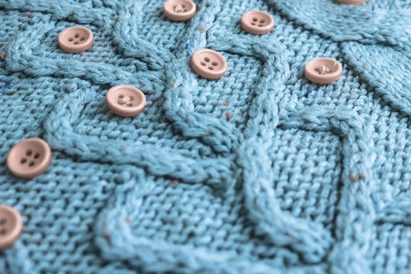 Beautiful texture of a soft warm natural sweater with a knitted pattern of yarn and red small round buttons for sewing. The background — Stock Photo, Image