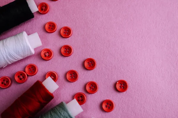 Schöne Textur mit vielen runden roten Knöpfen zum Nähen, Handarbeiten und Knäueln von Fadenspulen. Kopierraum. flach lag. rosa, lila Hintergrund — Stockfoto