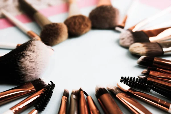 A frame from a set of beautiful different soft makeup brushes from natural lint for targeting beauty and applying a tonal foundation in a stand and copy space on a blue background — Stock Photo, Image