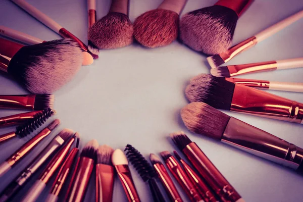 A frame from a set of beautiful different soft makeup brushes from natural lint for targeting beauty and applying a tonal foundation in a stand and copy space on a blue background — Stock Photo, Image