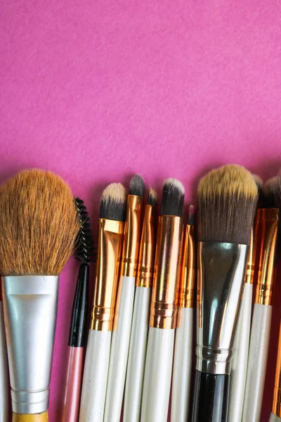 A set of beautiful different soft brushes for make-up from natural nap for beauty targeting and applying a tonal foundation in a stand and copy space on a pink, purple background