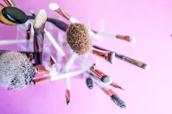 Un ensemble de belles brosses douces différentes pour le maquillage de la sieste naturelle pour le ciblage de la beauté et l'application d'une base tonale dans un stand et copier l'espace sur un fond rose, violet — Photo