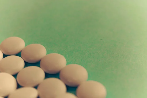 Текстура с белыми круглыми гладкими медицинскими таблетками, витаминами, антибиотиками и пространством для копирования на зеленом фоне. Плоский лежал — стоковое фото