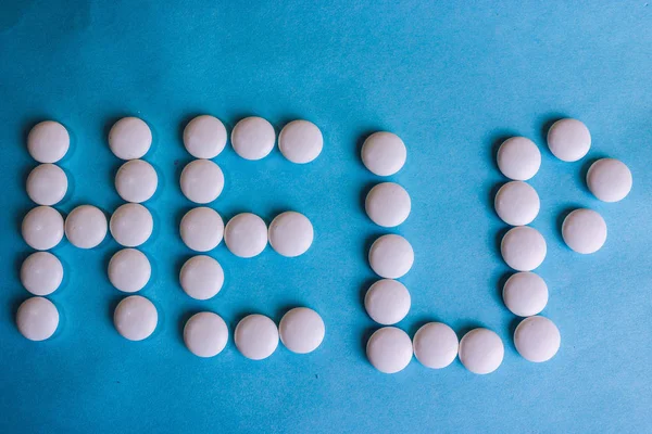 Beautiful inscription help made from white round smooth medical pills, vitamins, antibiotics and copy space on a bright blue background. Flat lay — Stock Photo, Image