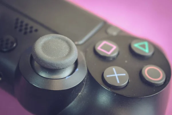 A beautiful black modern digital game joystick to control a video game console for video games with buttons and stick and copy space on a pink purple background — Stock Photo, Image