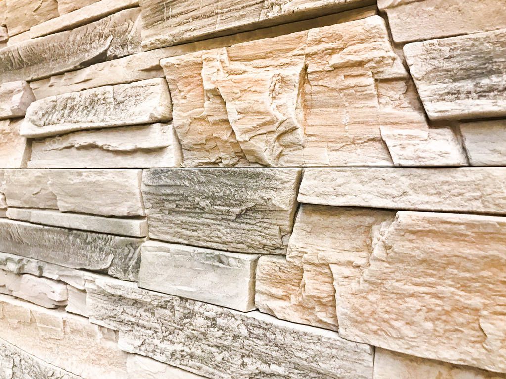 Beautiful texture of a decorative stone wall at an angle of construction gray textured relief stone with plaster with seams. The background