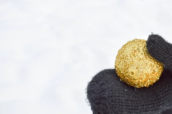 Όμορφη γιορτινή κομψό κίτρινο, Χρυσή στρογγυλές μπάλες, Χριστουγεννιάτικα διακοσμητικά για το νέο έτος, Χριστούγεννα βρίσκεται στα χέρια για μαύρα γάντια φόντο λευκό χιόνι το χειμώνα — Φωτογραφία Αρχείου