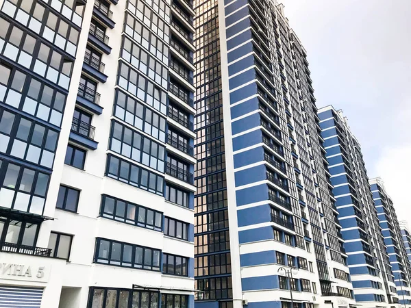 Blauer hoher moderner monolithischer Fachwerkbau, Haus, Neubau, ein Wolkenkratzer mit verspiegelten Fenstern vor blauem Himmel. Konzept: Umzug, Plattenbau, Wohnungsprobleme, moderne Architektur — Stockfoto