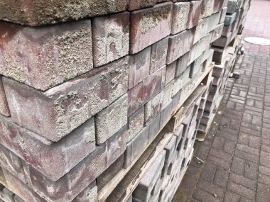 Yol İnşaatı, bir inşaat sahasında ahşap palet üzerinde kaldırım döşeme için kaldırım taşı kırmızı çimento kiremit