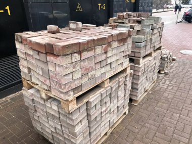 Yol İnşaatı, bir inşaat sahasında ahşap palet üzerinde kaldırım döşeme için kaldırım taşı kırmızı çimento kiremit