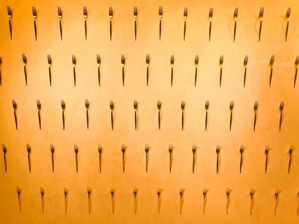 Рисунок из различных металлических вилок, столовые приборы на стене на желтом фоне. Текстура — стоковое фото