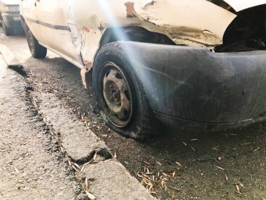 Eski beyaz paslı kırık araba karkas çizikler korozyon ile indirdi delinmiş jantlar ve ezik ve çizikler yolda atılmış ile bir yırtık kapalı tampon. Otomatik önemsiz