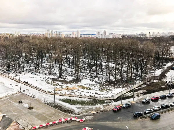 Widok z okna na starym cmentarzu miasta w parku z wysokości z drzew i domów w zimie. Panorama miasta — Zdjęcie stockowe