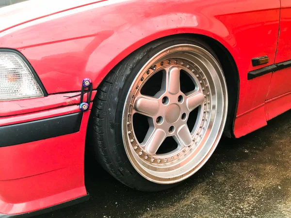 Beautiful big racing wheels of a sports red car with a very low ground clearance on cast shiny expensive alloy wheels in the style of Stans. Tuning cars — Stock Photo, Image