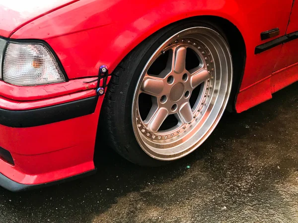 Beautiful big racing wheels of a sports red car with a very low ground clearance on cast shiny expensive alloy wheels in the style of Stans. Tuning cars — Stock Photo, Image