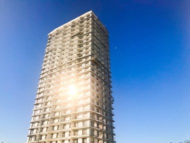 Büyük yüksek betonarme, panel, monolitik çerçeve, çerçeve-blok ev, bina, gökdelen, mavi gökyüzüne karşı pencerelerin güneşte bir parlama ile yeni bina