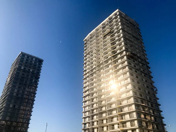 Zwei große hohe Stahlbetone, Platte, monolithischer Rahmen, Fachwerkhäuser, Gebäude, Wolkenkratzer, Neubauten mit Sonneneinstrahlung in den Fenstern gegen den blauen Himmel — Stockfoto
