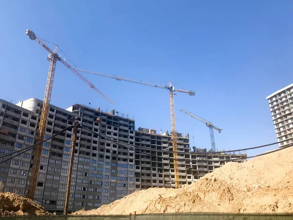 Bygning ved hjelp av byggekraner av høyarmert betong, panel, støperamme, rammehus, bygninger, skyskrapere, nye bygninger på bakgrunn av sandgrunn – stockfoto