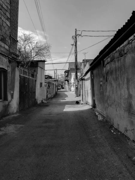 Strada stretta, corsia, tunnel con vecchie case, edifici ai lati in una zona povera della città, baraccopoli. Foto verticale — Foto Stock