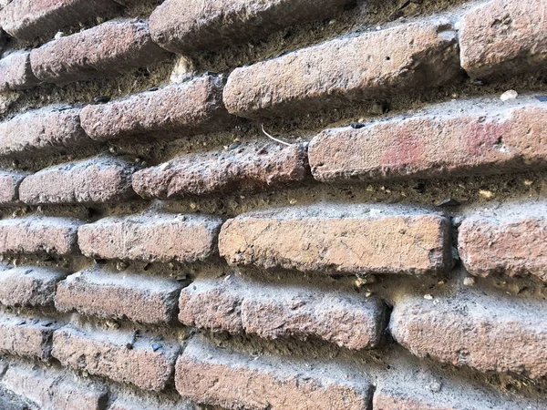 Texturen abgewinkelten alten schmalen konvexen Stein alten mittelalterlichen mittelalterlichen staubigen authentischen braunen Ziegel mit Nähten auf einer Ziegelwand. der Hintergrund — Stockfoto