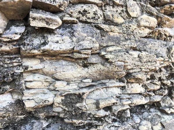 La consistenza del muro di pietra tagliente incrinato convesso grezzo naturale grigio soffio di vecchi mattoni di pietra antica nella roccia. Lo sfondo — Foto Stock