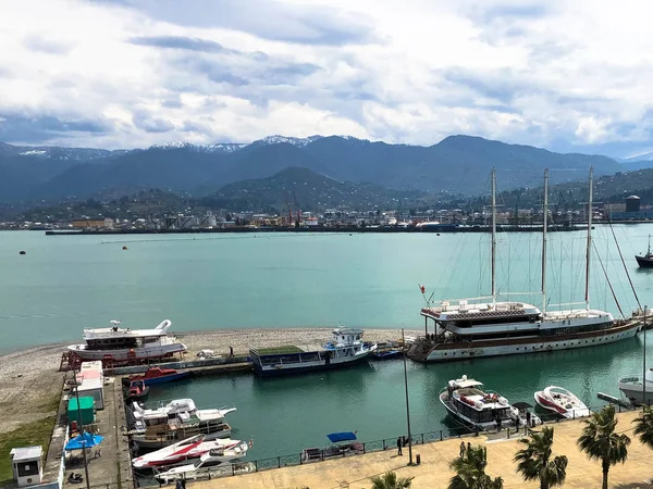 De nombreux navires, bateaux, paquebots de croisière dans le port et de l'eau sur la mer tropicale station estivale chaude avec des palmiers contre le ciel bleu et les hautes montagnes — Photo