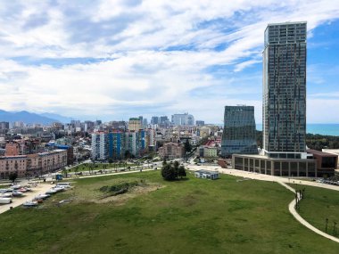 Modern bir büyük şehirde Yeşil park, yüksek cam evler, binalar, tropikal sıcak yazlık, dinlenme dağların mavi gökyüzüne karşı gökdelenler ile megalopolis