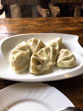 Lezzetli beyaz geleneksel büyük un Gürcü yuvarlak khinkali buğulanmış bir kafede ahşap bir masa üzerinde bir tabak yalan