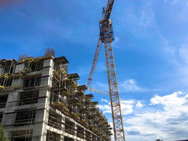 Mavi gökyüzüne karşı büyük bir vinç kullanarak iskele çok beton ve gaz silikat blokları monolitik çerçeve ev inşaatı