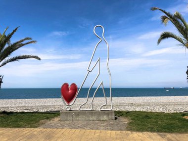 Batum Sahil Bulvarı veya Batum Plajı'nda bir tramvayda kalp taşıyan bir adamın soyut heykelleri, küçük mimari formları. Gürcistan, Batum, 17 Nisan 2019