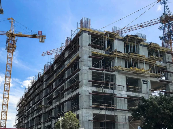 Construcción de una casa monolítica de bloques de silicato de hormigón y gas con montones de andamios utilizando una grúa grande contra un cielo azul —  Fotos de Stock