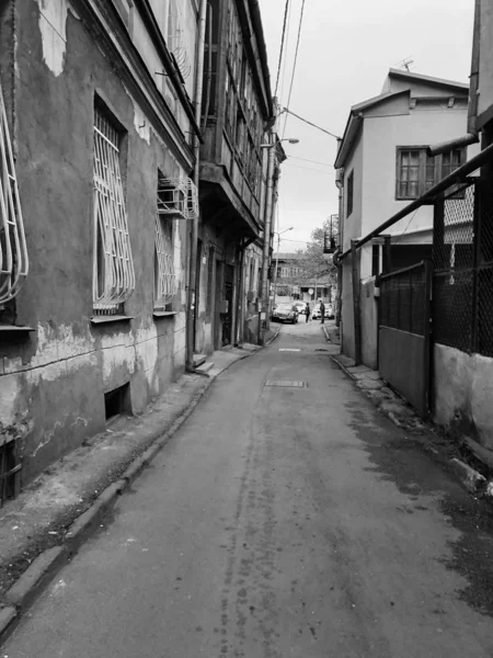 Belle vecchie case a tre piani marroni fatiscenti dell'edificio in una strada stretta di ciottoli con finestre e balconi, terrazze baraccopoli nella vecchia area urbana della città — Foto Stock