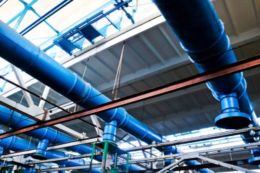 Mavi metal demir büyük giriş boruları ve egzoz havalandırması ile endüstriyel kimyasal petrokimya makine yapımı rafinerisindeki atölyede tavan