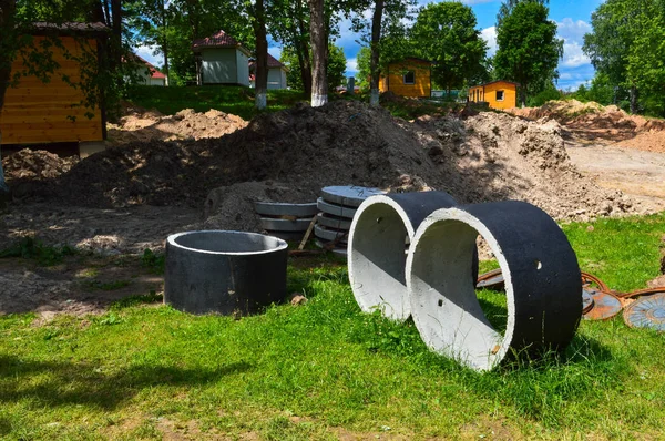 Velké kruhové betonové cementové kamenné kroužky pro výstavbu kanalizačních jamek během výstavby domu — Stock fotografie