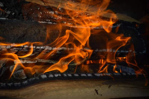 Holz, das heiß verkohlte Bretter aus Holzstämmen in einem Feuer mit Feuerzungen und Rauch verbrennt. Textur, Hintergrund — Stockfoto