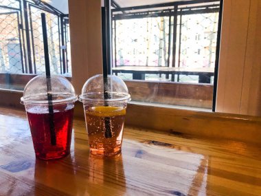 Plastik kırmızı ve sarı ferahlatıcı soğuk lezzetli tatlı ahududu çilek kiraz portakal şeftali limonlimonata doğal bir saman ve şurup kabarcıklar ile iki bardak